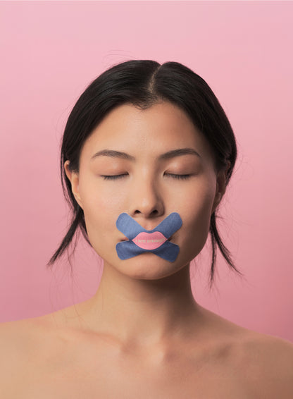 Woman with a cross mouth tape and pink lips on a pink background