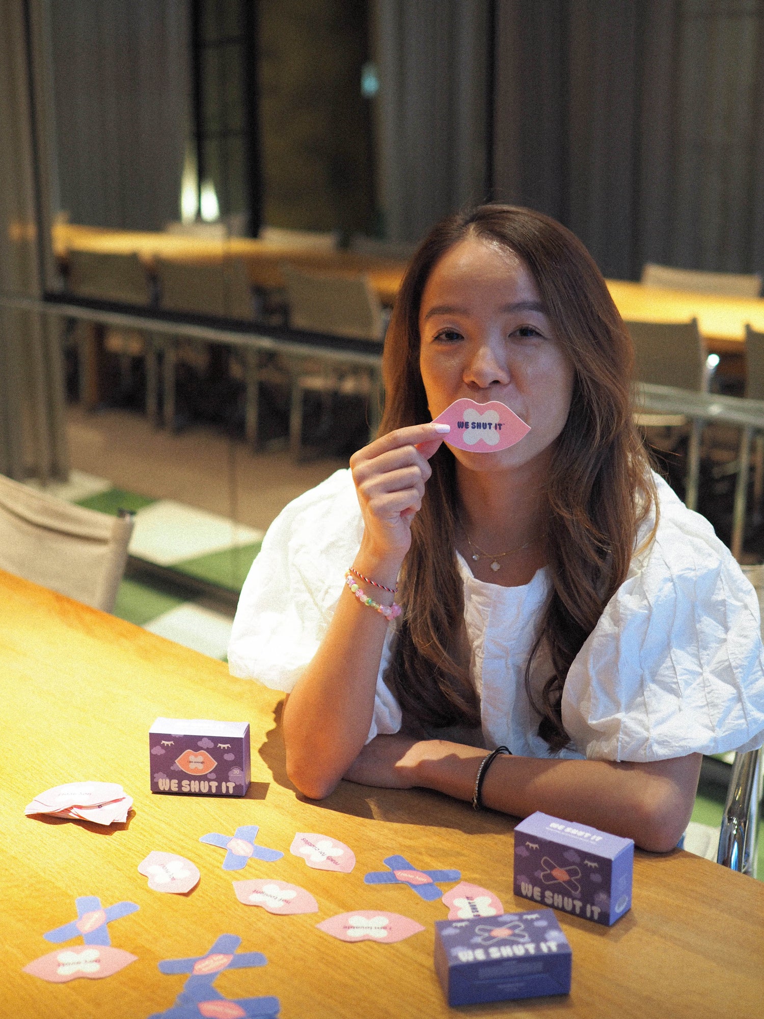 We Shut It mouth tape founder holding a bamboo fibre mouth tape and several mouth tapes spread on the table.